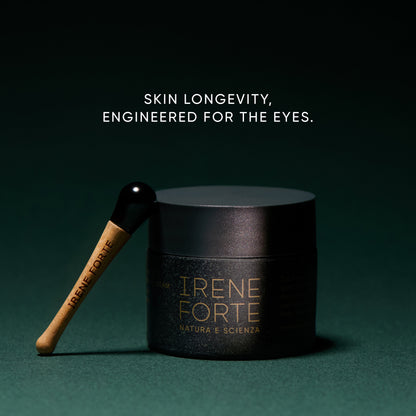 Black skincare jar with wooden applicator on a dark green background, featuring the brand &